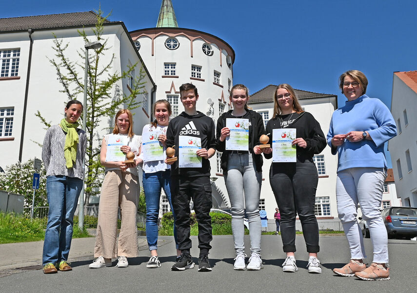 7 Personen stehen vor dem Schulgeäbude der Brede und 5 davon halten eine Urkunde in der Hand.