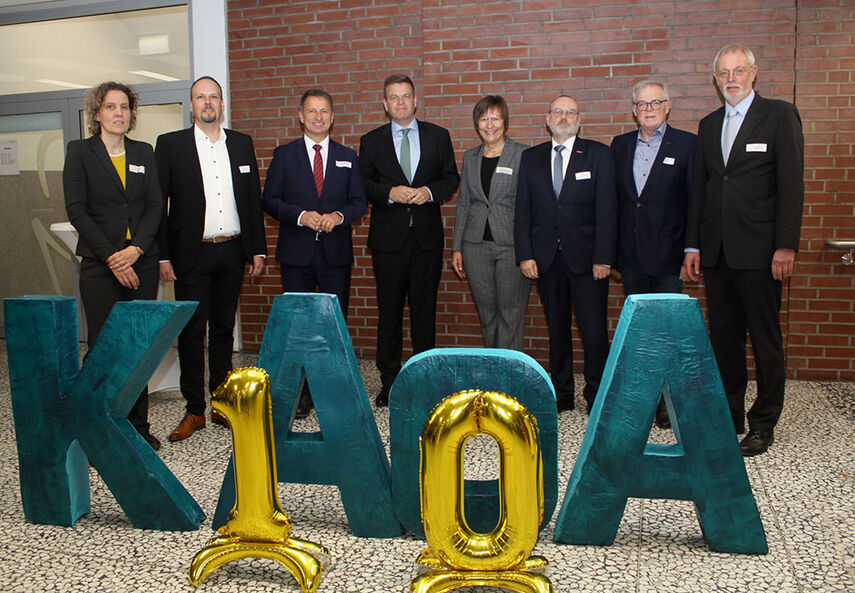 8 Personen stehen vor einem KAoA Logo